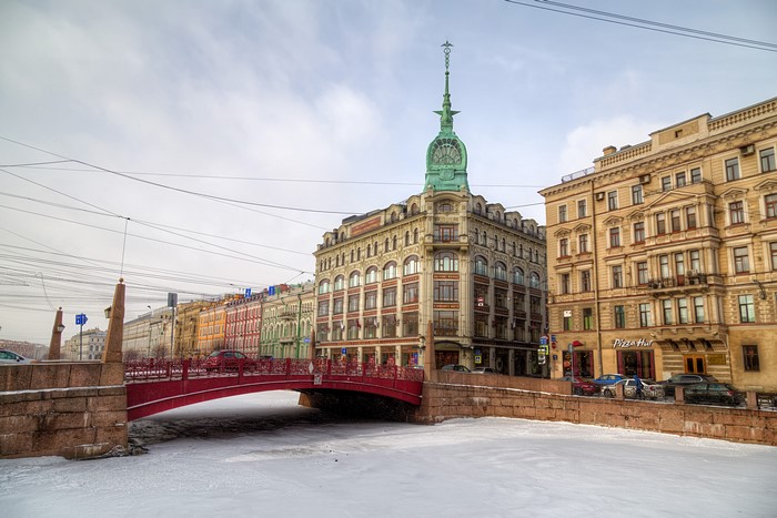 St. Petersburg, Russia: Snow-covered canal with red bridge and historic buildings