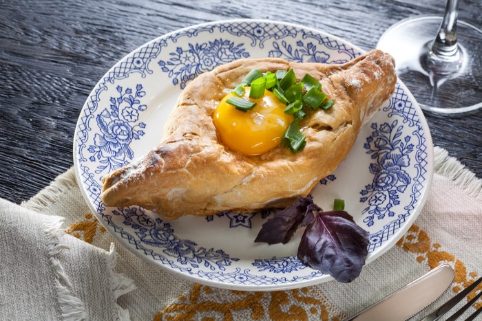 Khachapuri with egg and green onions on a plate