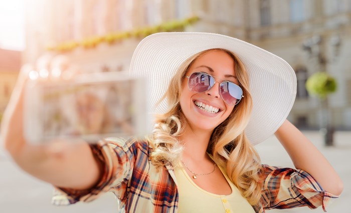 Blonde girl in hat and sunglasses taking a selfie