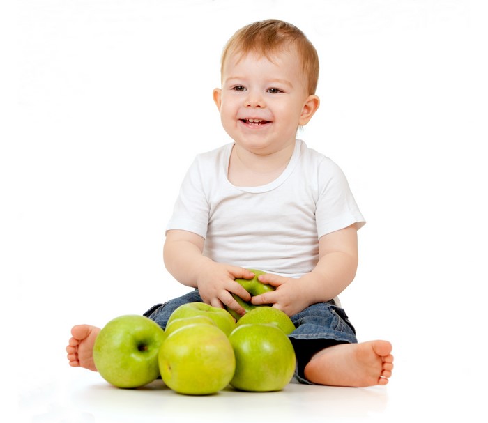 Baby boy sitting with green apples