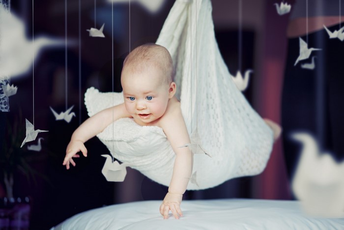 Baby in a white hammock with origami birds