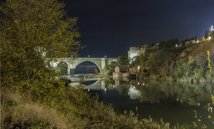 Bridge over river at night with fortress