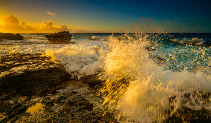 Waves crashing on rocks at sunset in Hawaii