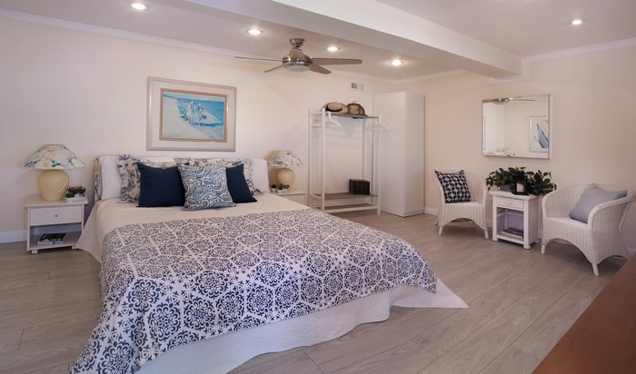 Bedroom with bed, pillows, armchair, and ceiling fan