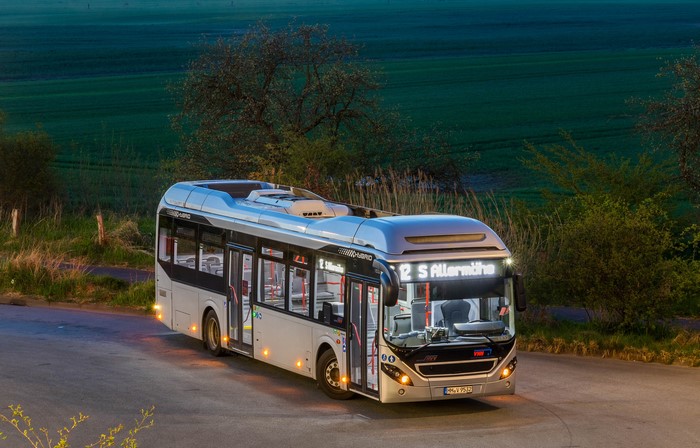Hybrid bus on a road at dusk