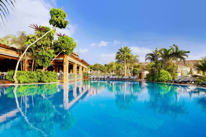 Resort swimming pool with palm trees and lounge chairs in Tenerife