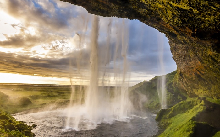 View from behind a waterfall at sunset