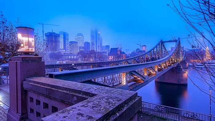 Frankfurt skyline and bridge over river at dusk