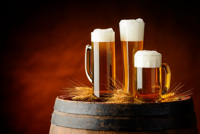 Three Mugs of Beer on a Barrel with Wheat