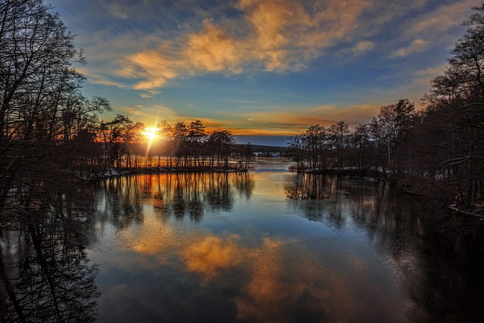 Sunset over a river with trees and clouds