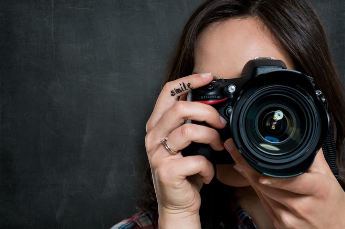 Photographer with camera and 'smile' tattoo on finger