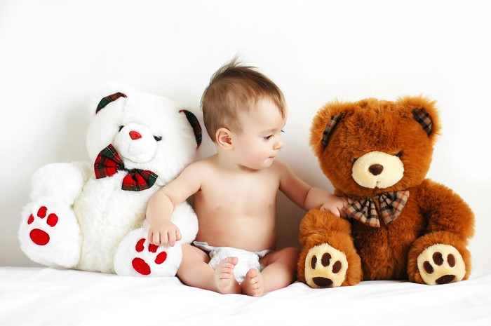 Baby sitting between two teddy bears