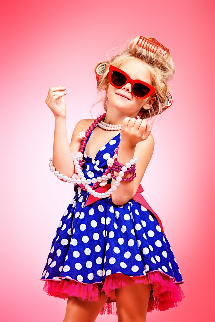 Little girl with curlers and sunglasses wearing a polka dot dress