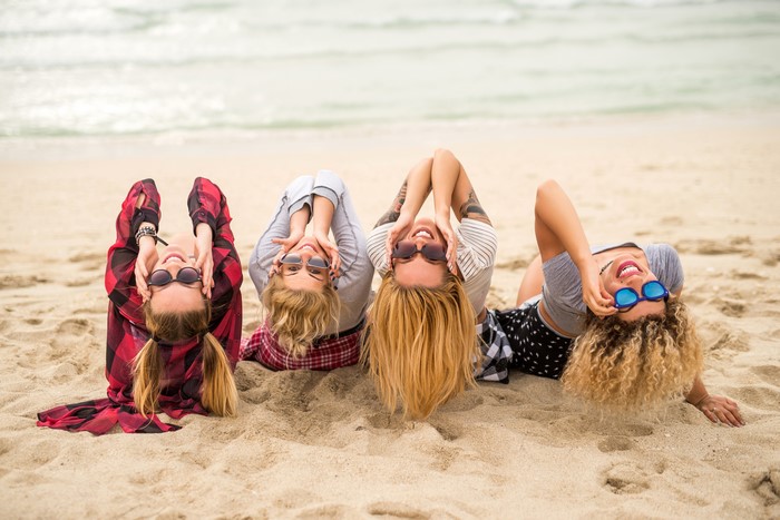 Four friends lying on the beach