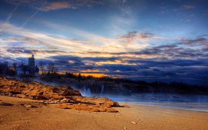Lighthouse on a rocky coast at sunset