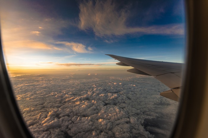 Airplane wing over clouds at sunset