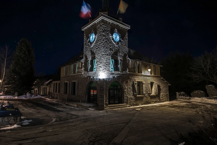 Night view of a stone building with a clock tower in Font-Romeu-Odeillo-Via, France