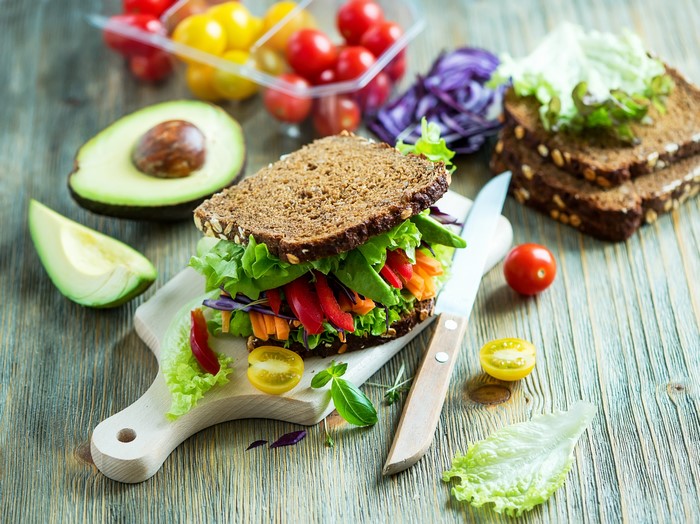 Vegetable sandwich with avocado and cherry tomatoes on a cutting board