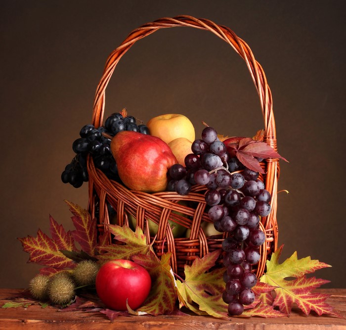 Still life of fruit in a wicker basket with autumn foliage