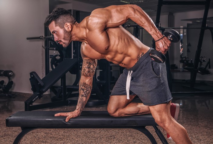 Man doing dumbbell triceps extension in gym