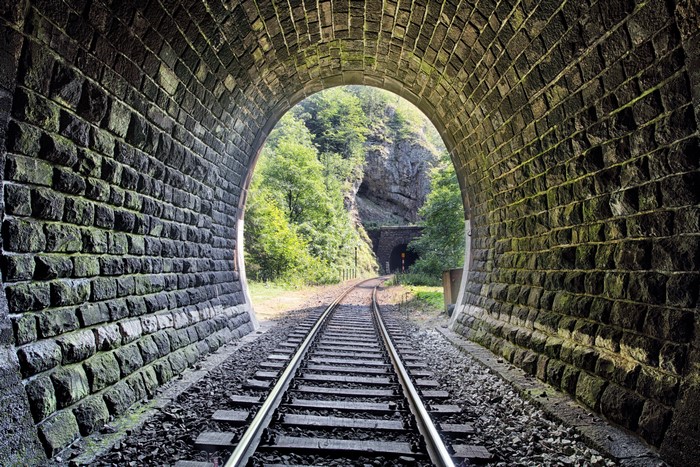 Stone railroad tunnel with tracks leading to another tunnel