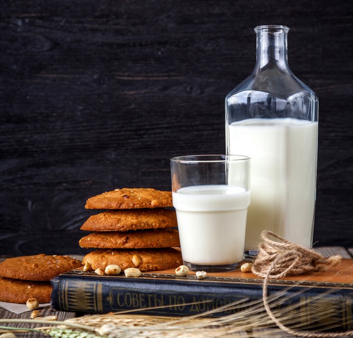 Milk bottle, glass, cookies, and book on wooden table