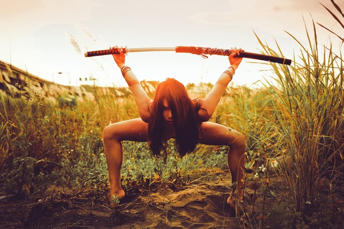 Woman holding a katana in a field
