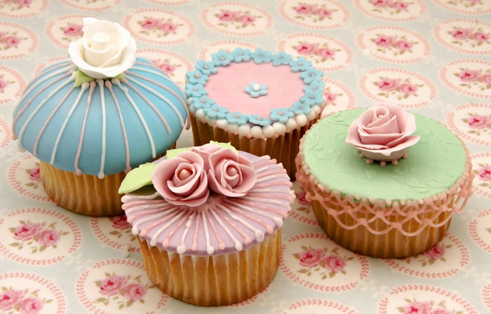 Four decorated cupcakes with roses and floral designs