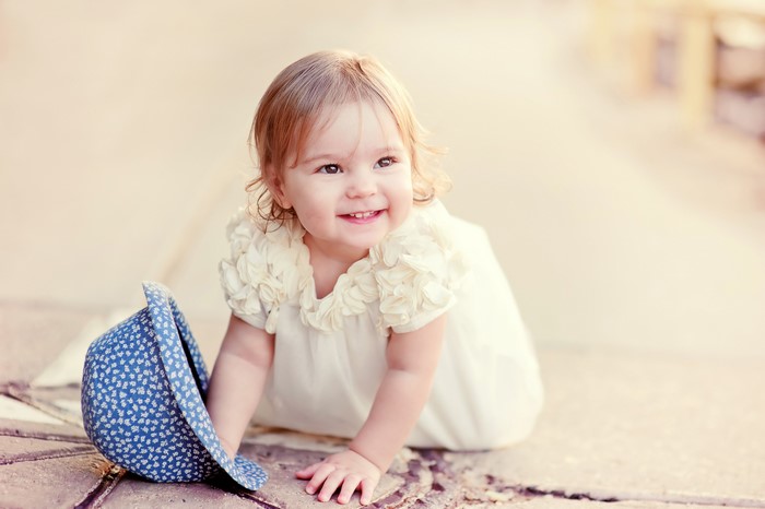 Baby girl in a white dress with a blue hat