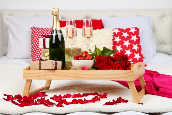 Champagne, Strawberries, Roses, and Gifts on a Bed