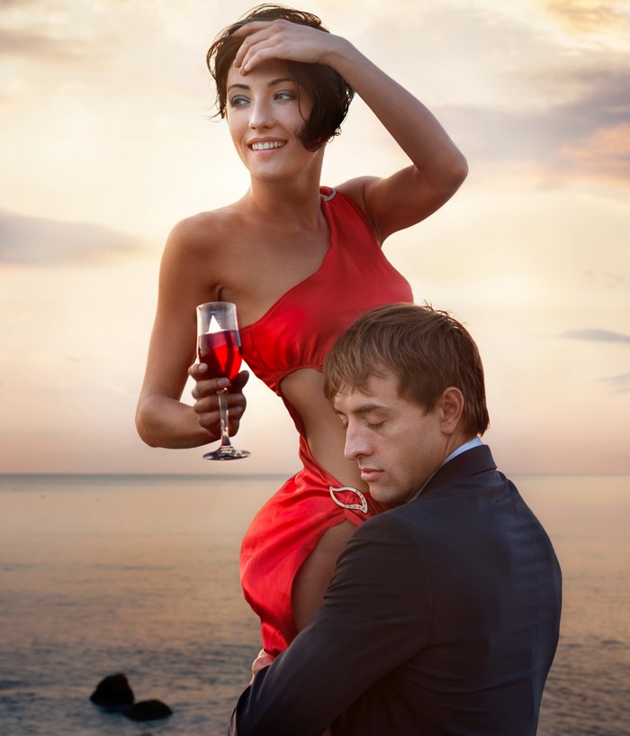 Couple with wine glass by the sea at sunset
