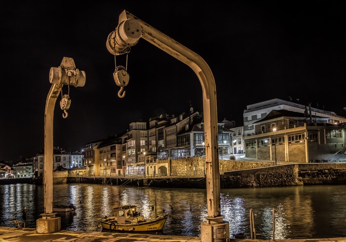 Night view of cranes and boats in Luanco, Asturias