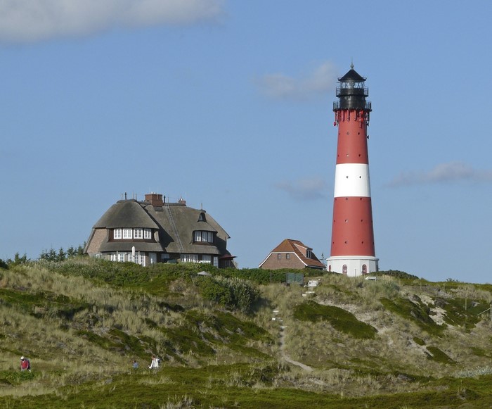 Lighthouse and thatched house on a grassy dune