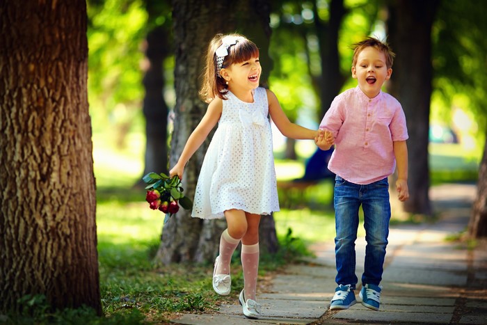 A girl with flowers and a boy walking in a park
