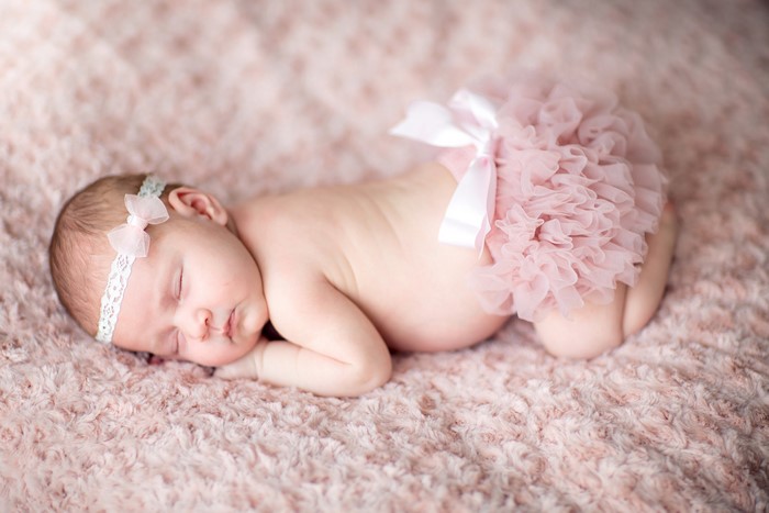 Newborn baby girl sleeping on pink blanket