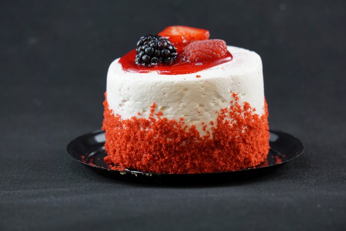 Red velvet cake with berries on a black saucer