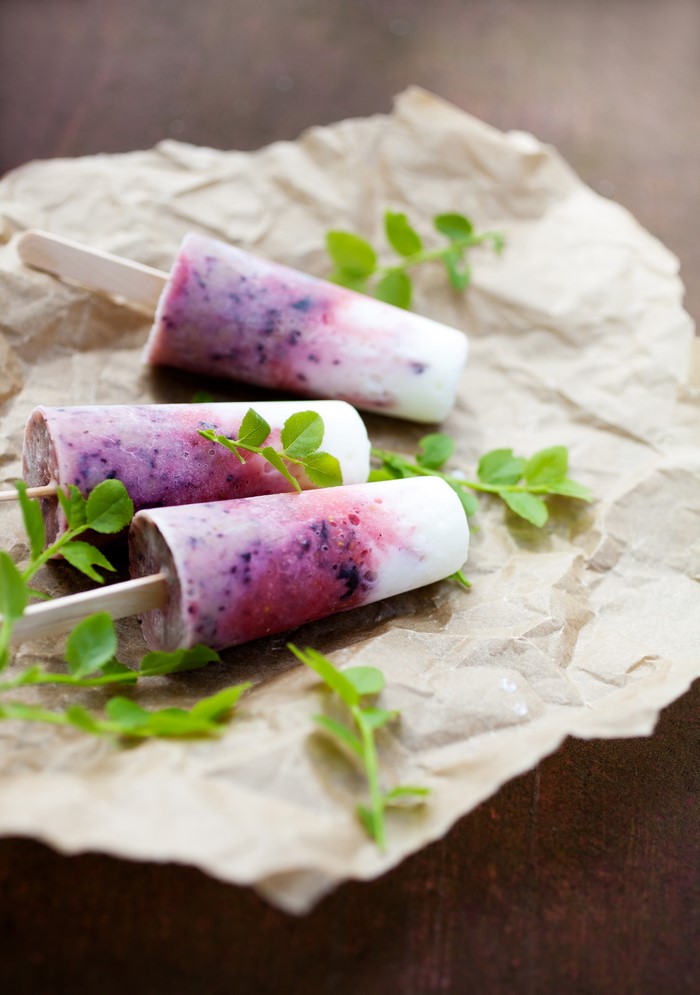 Three berry and yogurt popsicles on crumpled brown paper