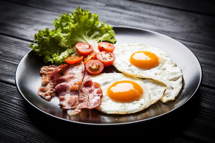Fried eggs with bacon, tomatoes, and lettuce on a plate