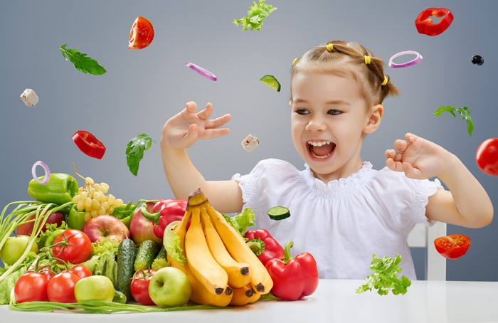Girl with flying vegetables and fruits