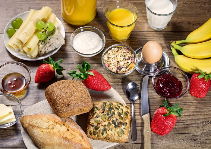 Breakfast spread with bread, cheese, fruit, and juice