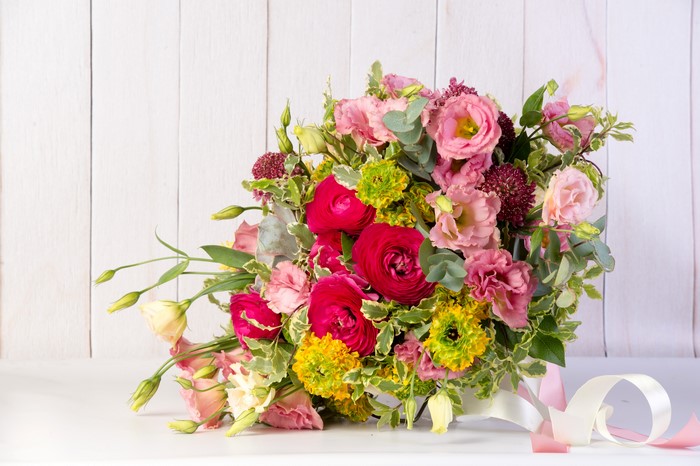 Bouquet of Ranunculus and Eustoma flowers on wood planks