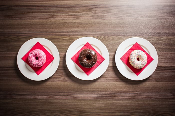 Three donuts on plates with red napkins
