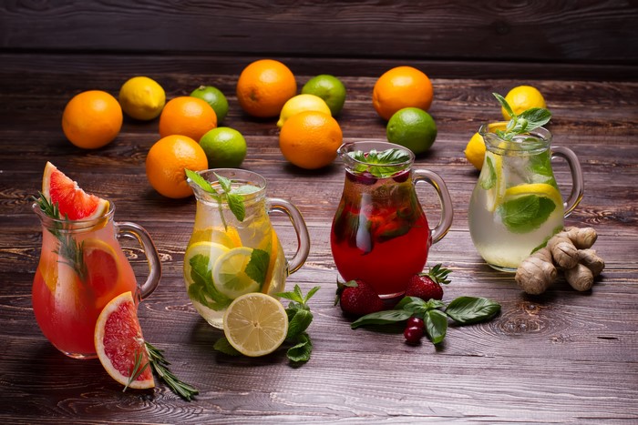 Four pitchers of fruit infused water with citrus and berries