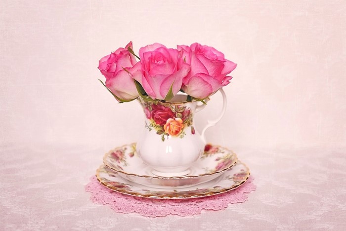 Pink roses in a floral jug on saucers