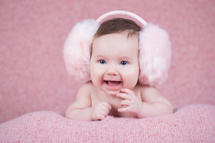 Baby wearing pink earmuffs smiling