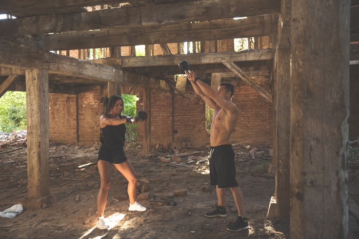 Man and woman doing kettlebell workout in abandoned building