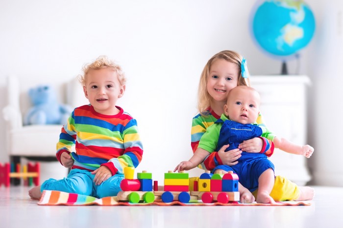 Three children playing with a toy train