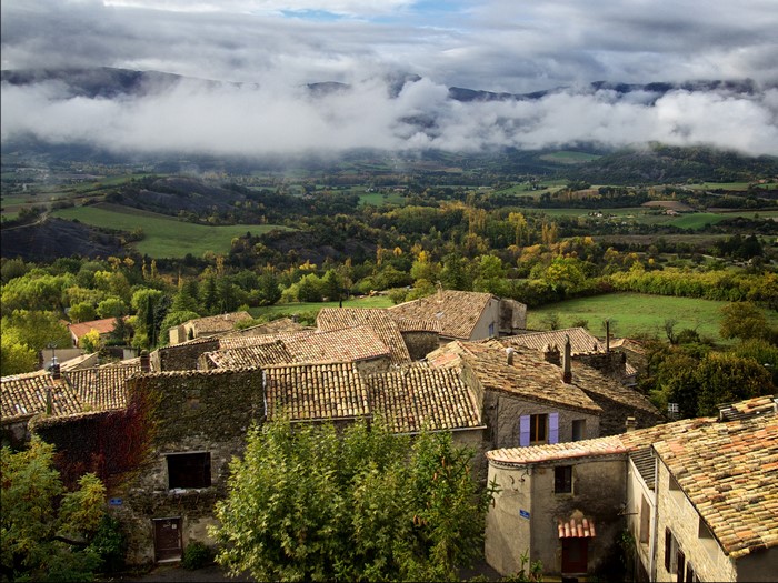 Village rooftops in Rosans, France with misty mountains