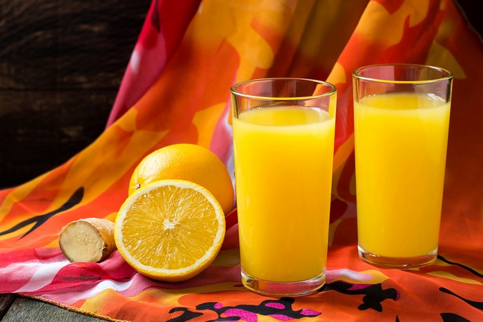 Two glasses of orange juice with oranges and ginger