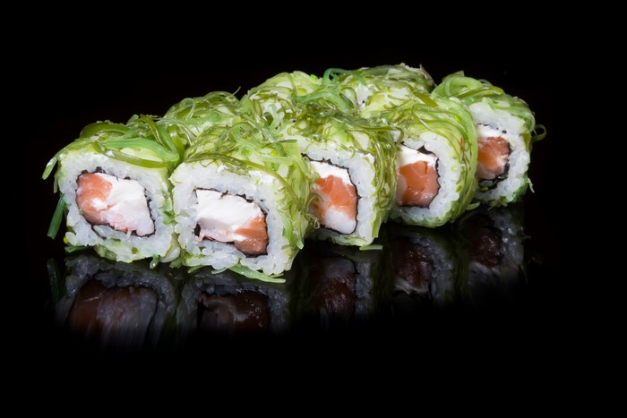 Sushi rolls with salmon and cream cheese on black background